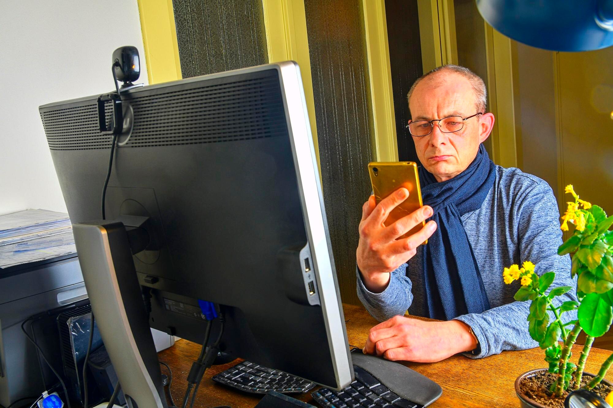 Mężczyzna w średnim wieku z okularami siedzący przy biurku Dojrzały mężczyzna używający telefonu komórkowego Senior koncepcja Człowiek osobiście