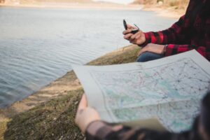 Piesi z mapą i kompasem nad jeziorem