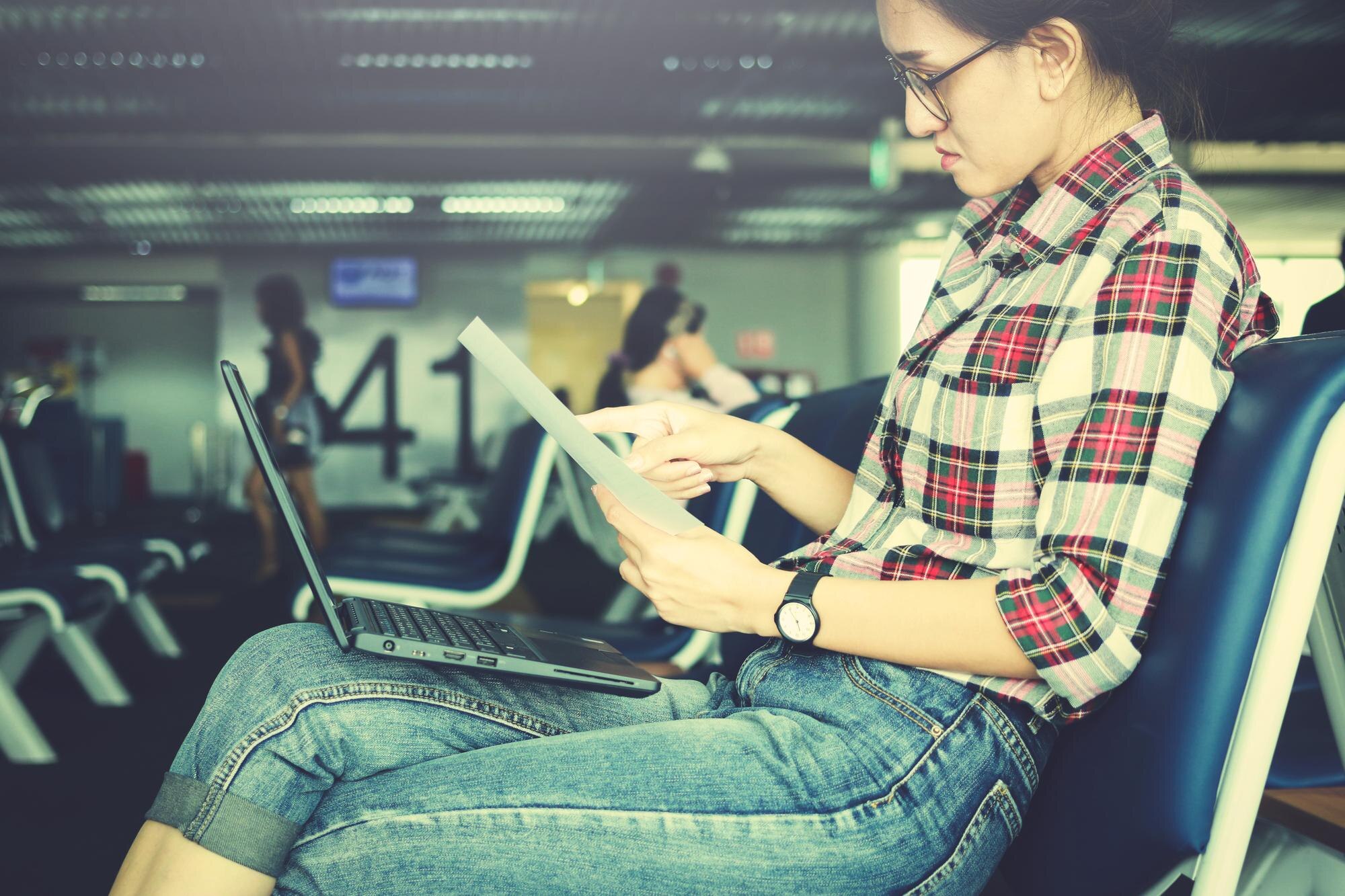 Kobieta wykonująca papierkową robotę przy użyciu laptopa na lotnisku