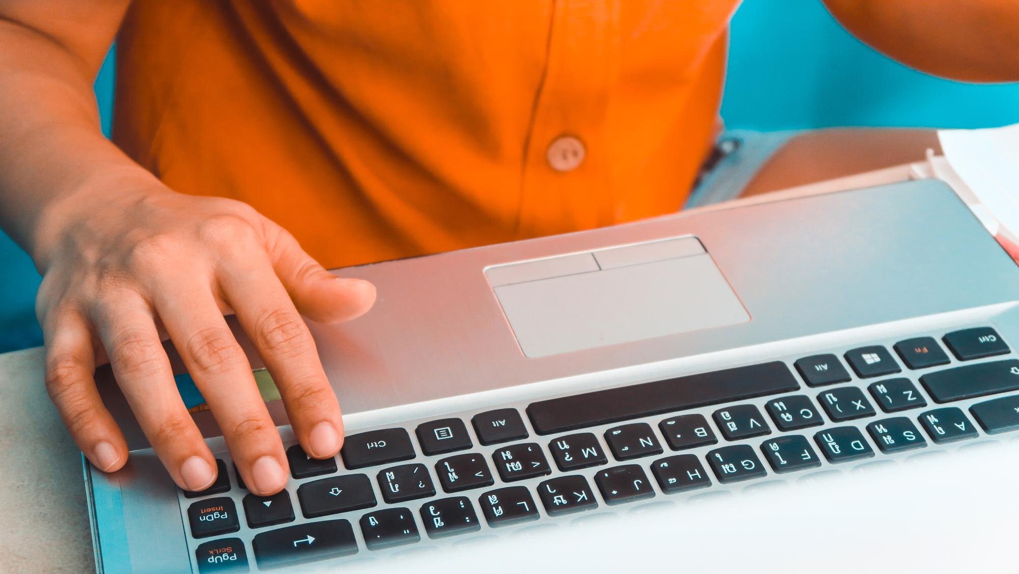 Środkowa sekcja mężczyzny używającego laptopa na biurku