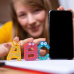 Młoda kobieta trzyma smartphone z literami abc