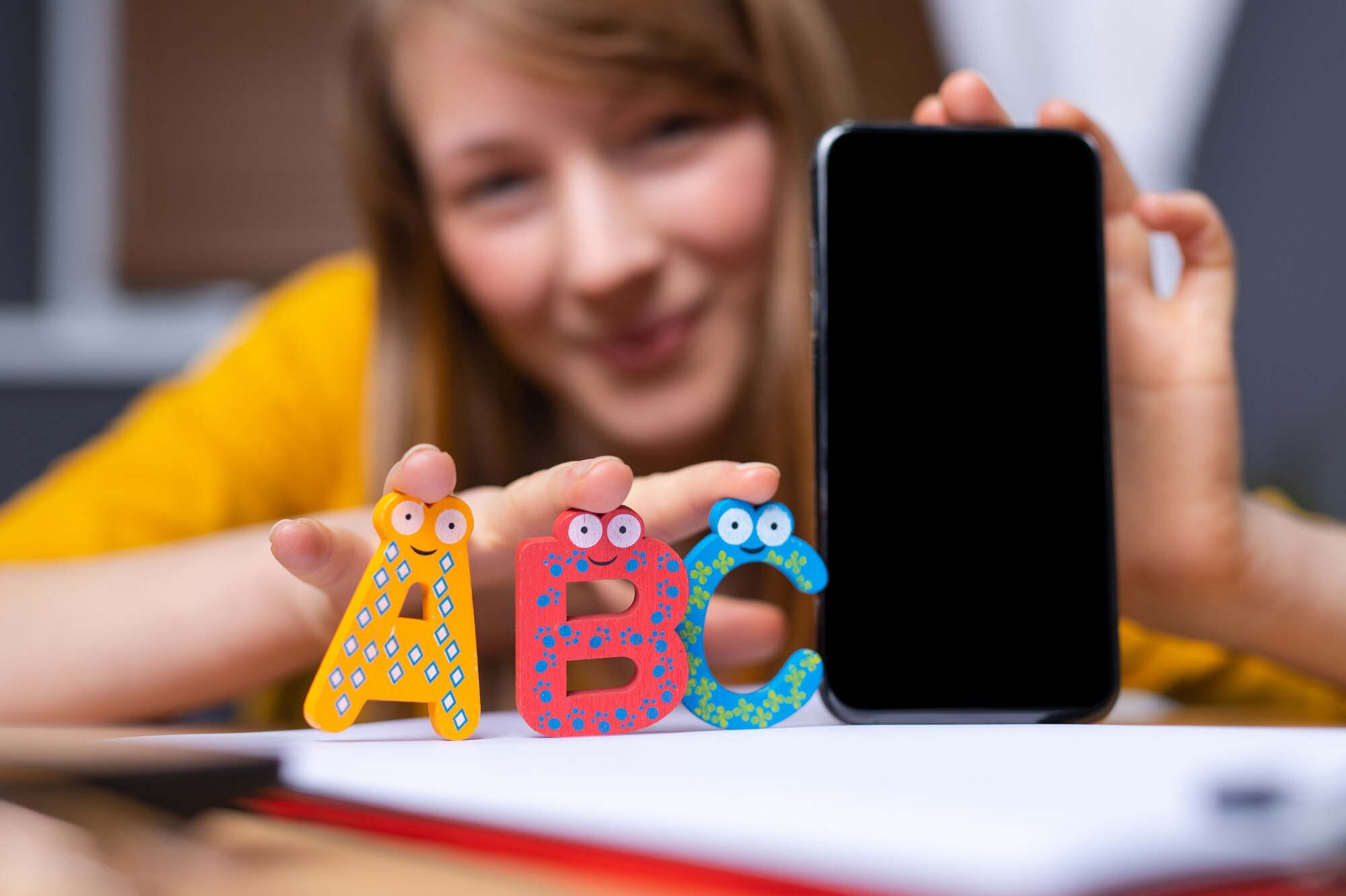 Młoda kobieta trzyma smartphone z literami abc