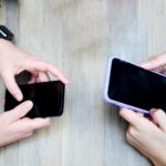 Kobiece dłonie z telefonami komórkowymi na stole z góry