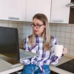 kobieta w kraciastej koszuli i okularach przy filiżance kawy