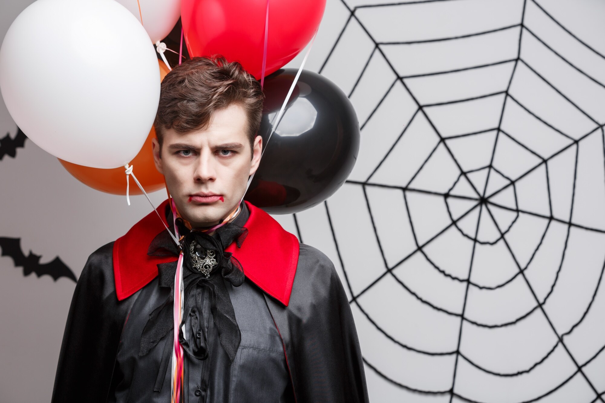 Portret przystojny caucasian w wampira Halloween kostiumu z kolorowym balonem.