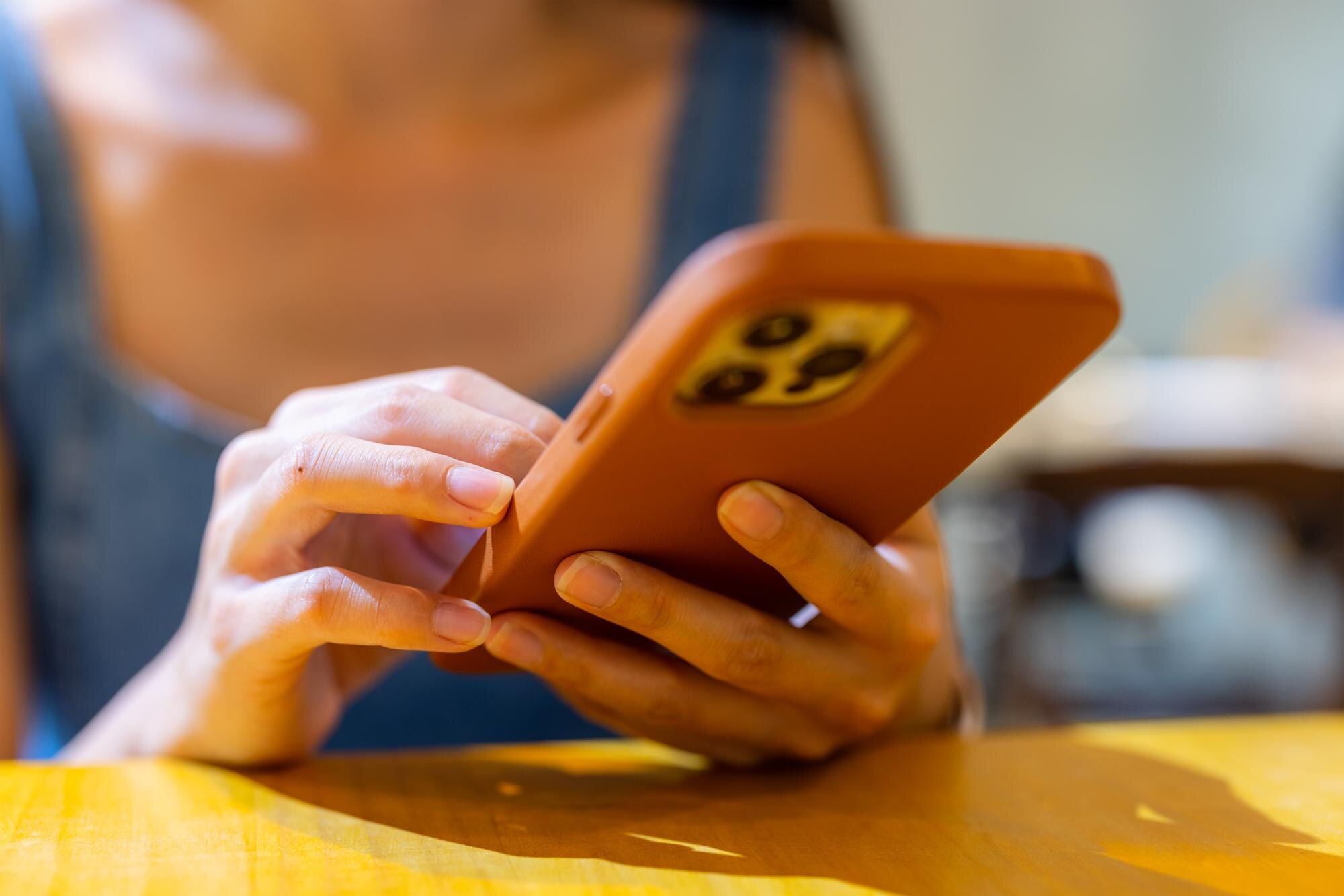 Kobieta używa telefonu komórkowego w kawiarni.