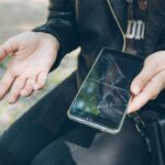 Telefon z pękniętym ekranem w ręku bez przypadku gwarancji