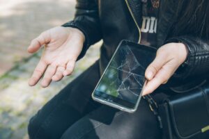 Telefon z pękniętym ekranem w ręku bez przypadku gwarancji