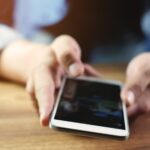 zbliżenie mężczyzna bawić się telefon komórkowego na drewnianym biurku