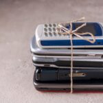 Stos telefonów komórkowych przewiązany sznurkiem na szarym tynku