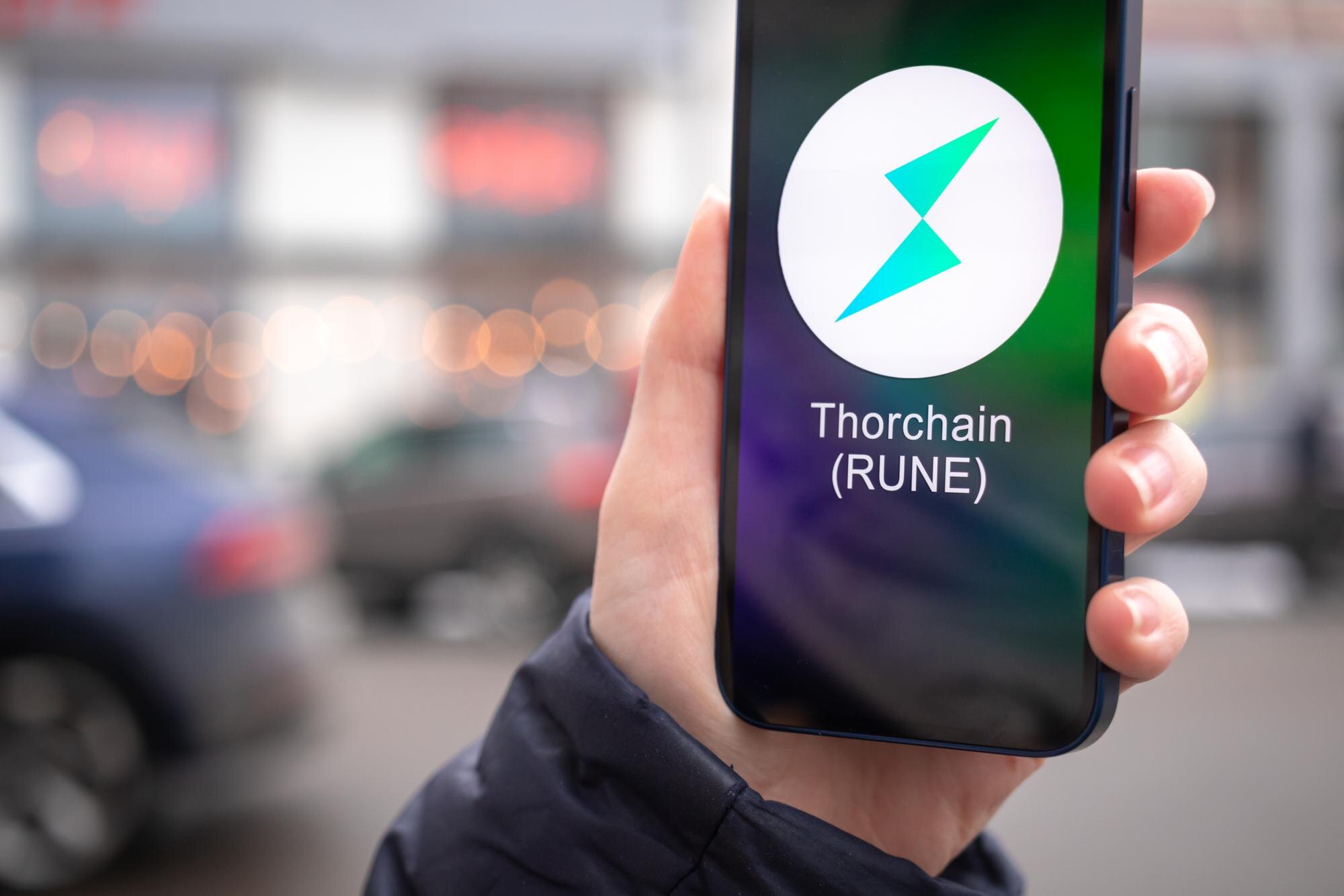 Charków Ukraina 2 lutego 2022 Thorchain RUNE symbol monety Handel z kryptowalutą cyfrową i wirtualną bankowością mobilną Ręka z ekranem smartfona z zbliżeniem ikony krypto