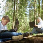 Matka i syn z laptopem w lesie w lecie gruby młody mądry nastolatek i kobieta pracująca z