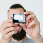 Nowoczesna technologia tworzenia treści wideo człowiek trzymający kamerę akcji i nagrywający sam sprzęt i narzędzia blogera