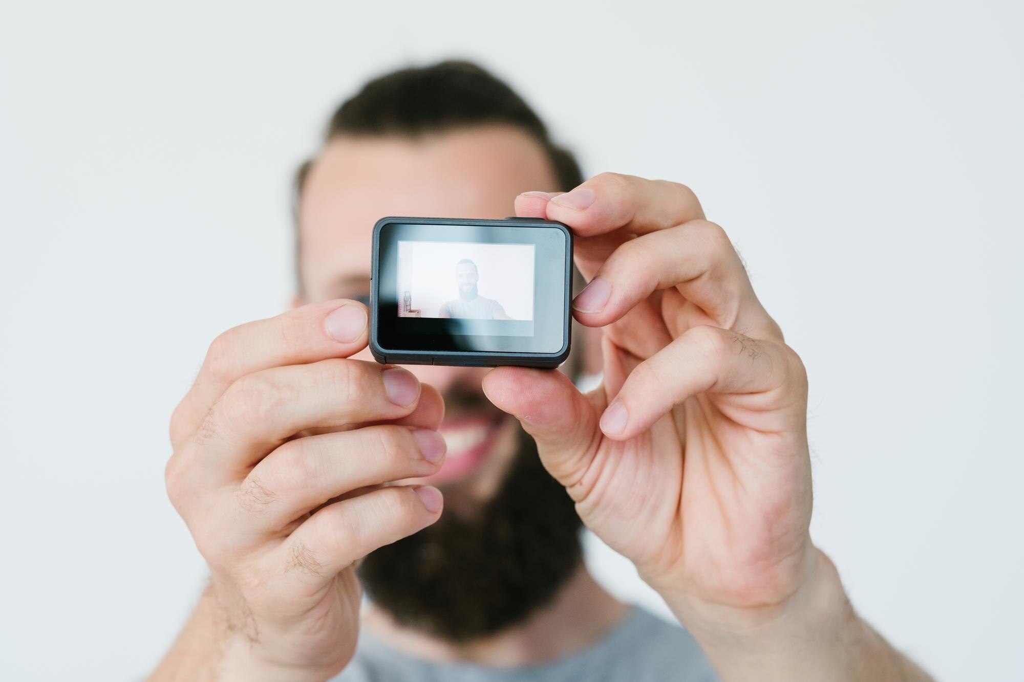 Nowoczesna technologia tworzenia treści wideo człowiek trzymający kamerę akcji i nagrywający sam sprzęt i narzędzia blogera