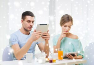 koncepcja żywności, rodziny, ludzi i technologii - para z komputerami typu tablet PC czytająca wiadomości i jedząca śniadanie w domu
