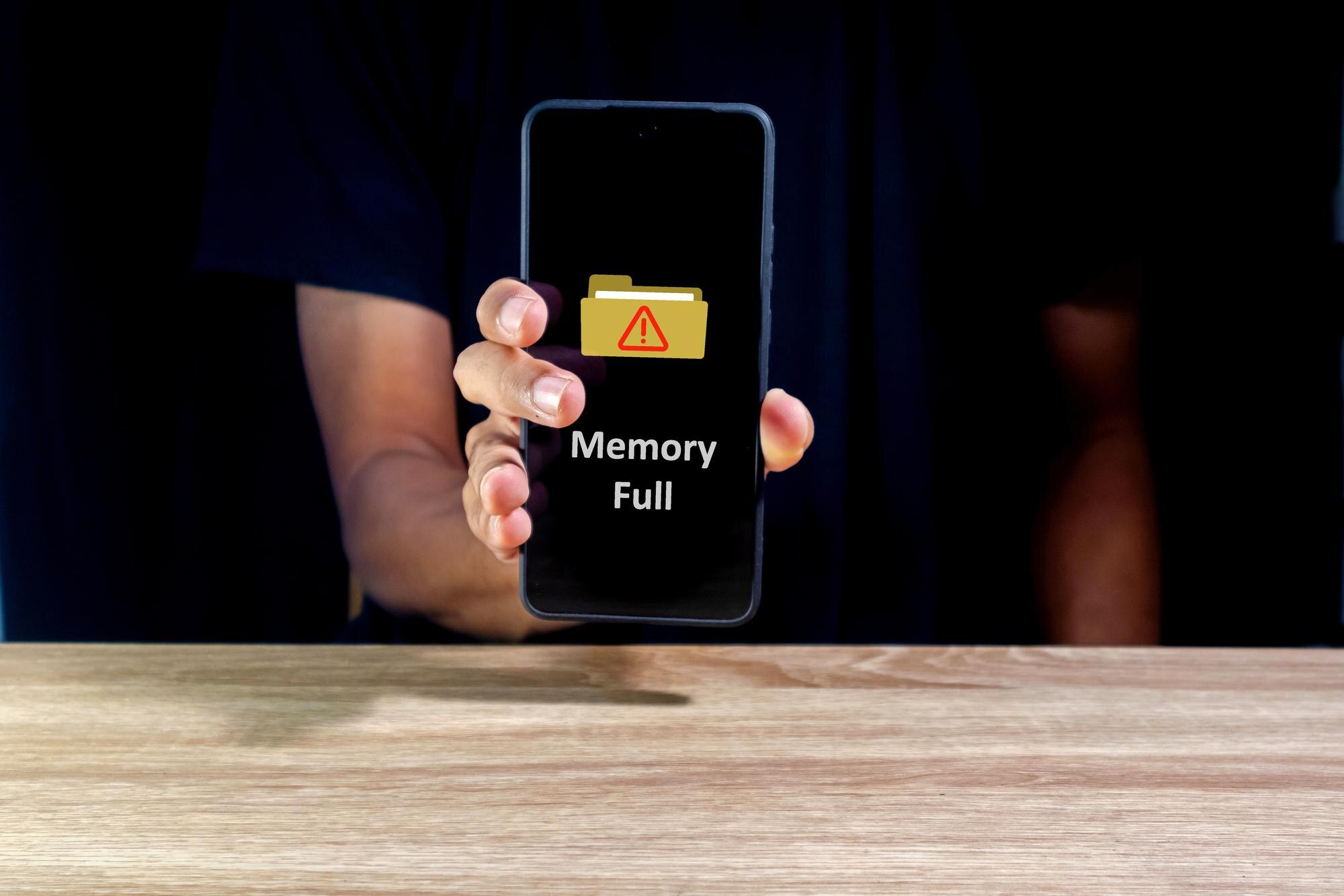 Mężczyzna trzymający smartfon z pamięcią pełnym powiadomieniem na ekranie