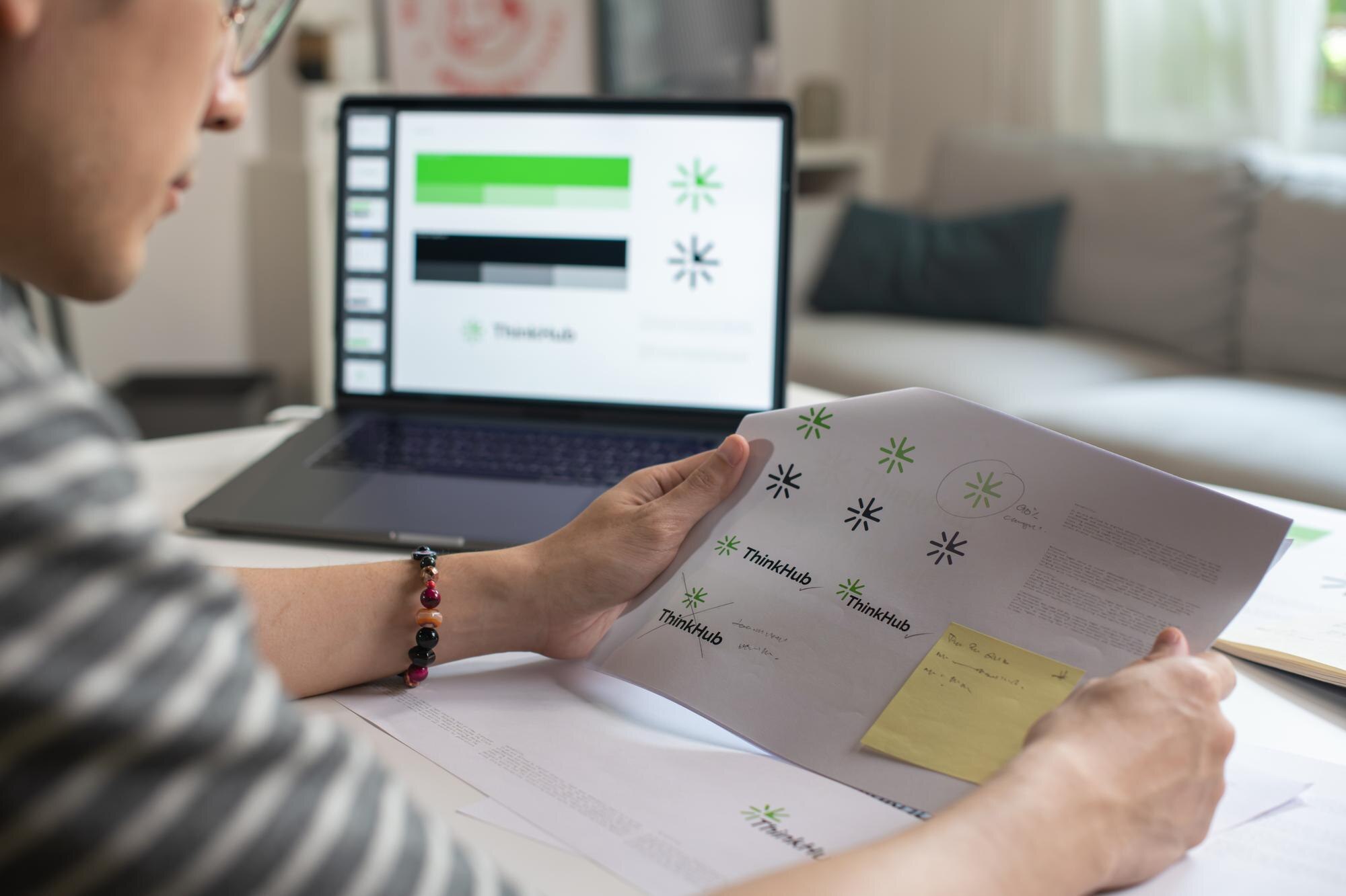 Mężczyzna azjatycki projektant graficzny pracujący w biurowym studiu projektujący logo i prezentujący proces projektowania tożsamości korporacyjnej i logo