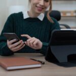Bliska Biznes kobieta za pomocą kalkulatora i telefonu do matematyki finansów na drewnianym biurku w biurze i działalności gospodarczej w tle statystyki rachunkowości podatkowej i koncepcja badań analitycznych