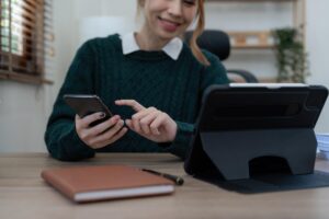 Bliska Biznes kobieta za pomocą kalkulatora i telefonu do matematyki finansów na drewnianym biurku w biurze i działalności gospodarczej w tle statystyki rachunkowości podatkowej i koncepcja badań analitycznych