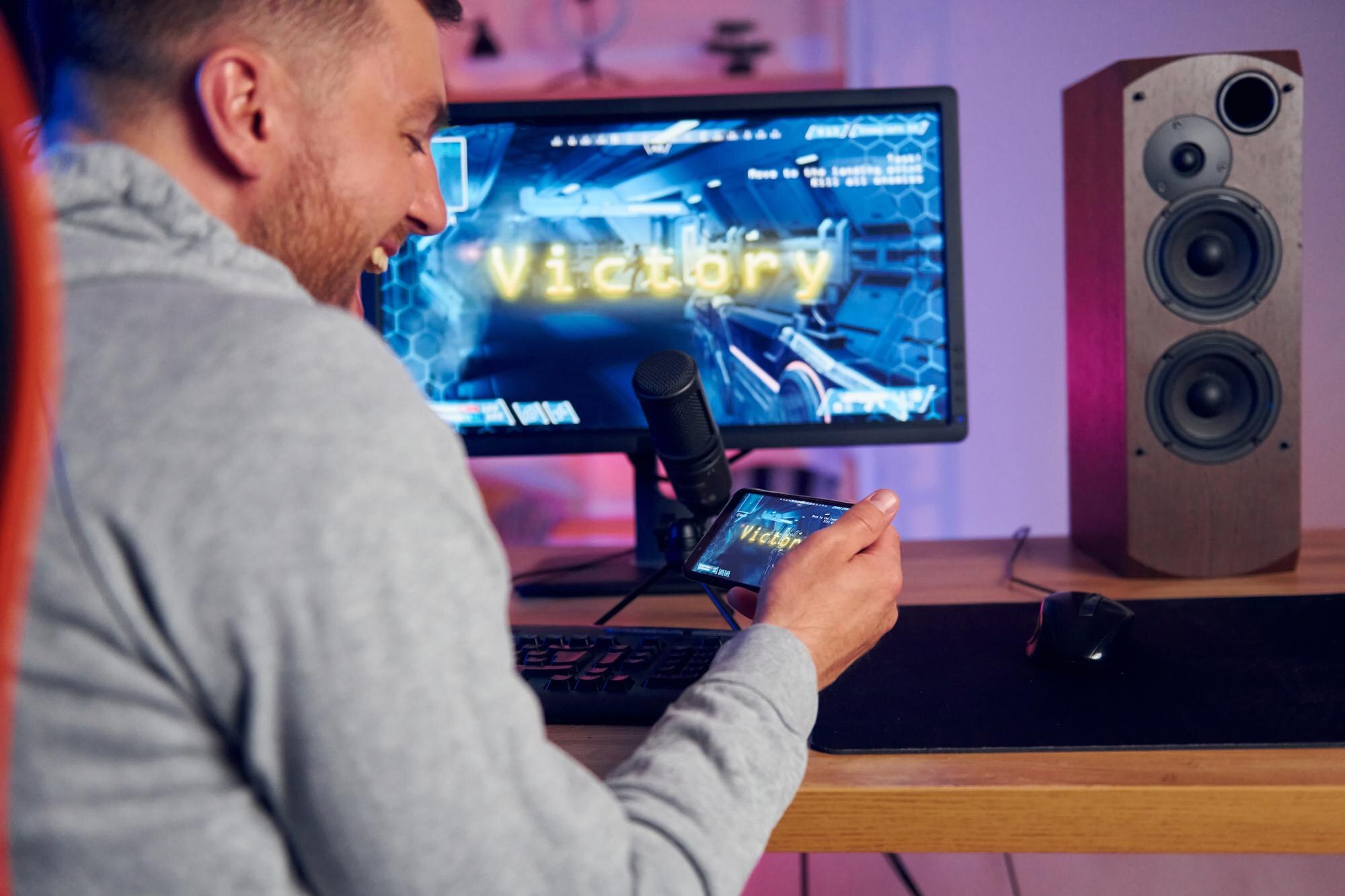 Zwycięski szczęśliwy człowiek świętuje Streamer online grający w strzelankę FPS w domu