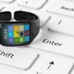 Smartwatch z aplikacjami na ekranie ustawionym na białej klawiaturze