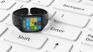 Smartwatch z aplikacjami na ekranie ustawionym na białej klawiaturze