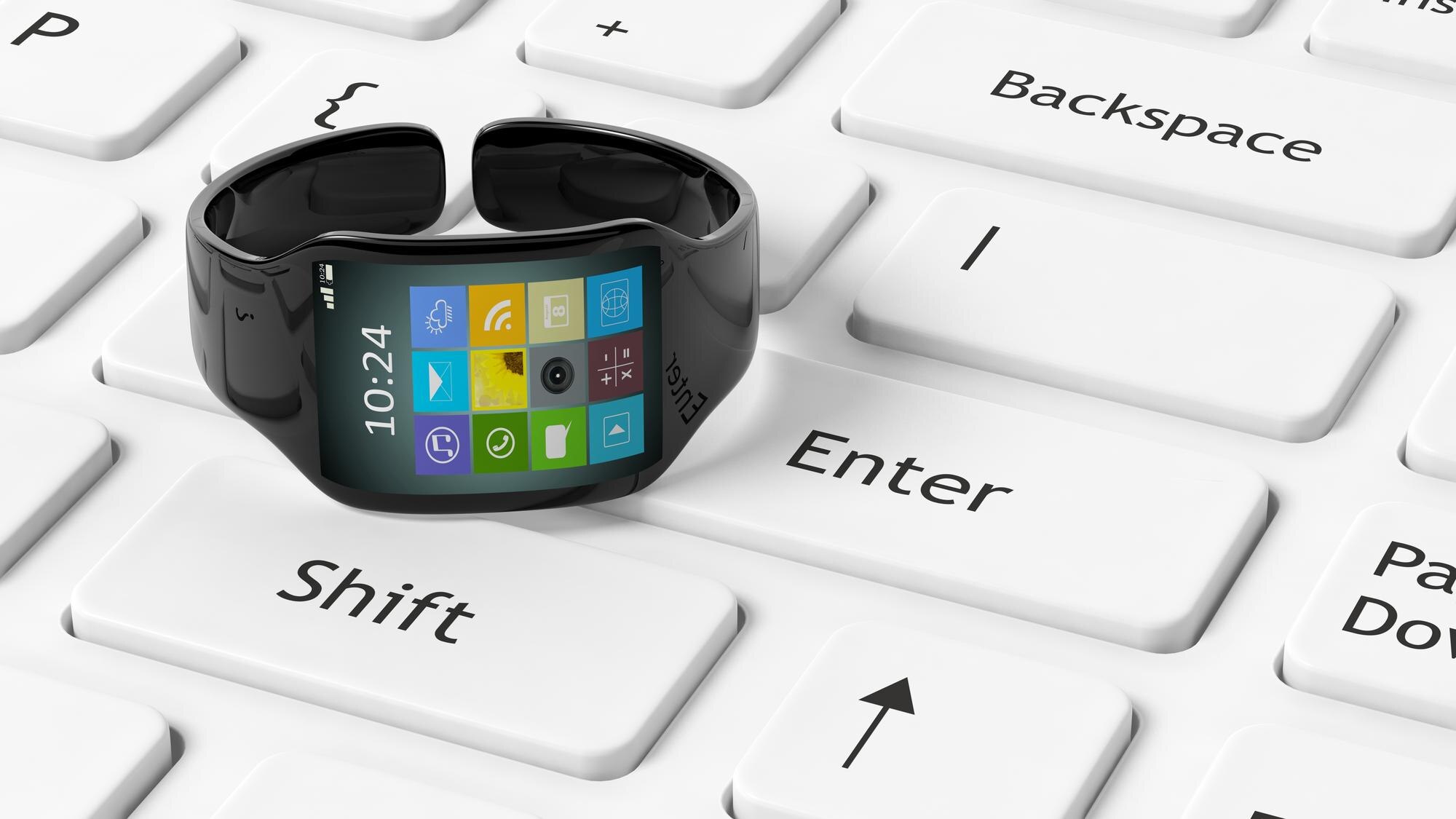 Smartwatch z aplikacjami na ekranie ustawionym na białej klawiaturze