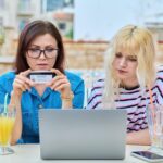 Matka i nastoletnia córka robią razem zakupy online za pomocą laptopa