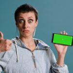 Zadowolona szczęśliwa kobieta pokazuje wyizolowany ekran klucza chromatycznego na smartfonie