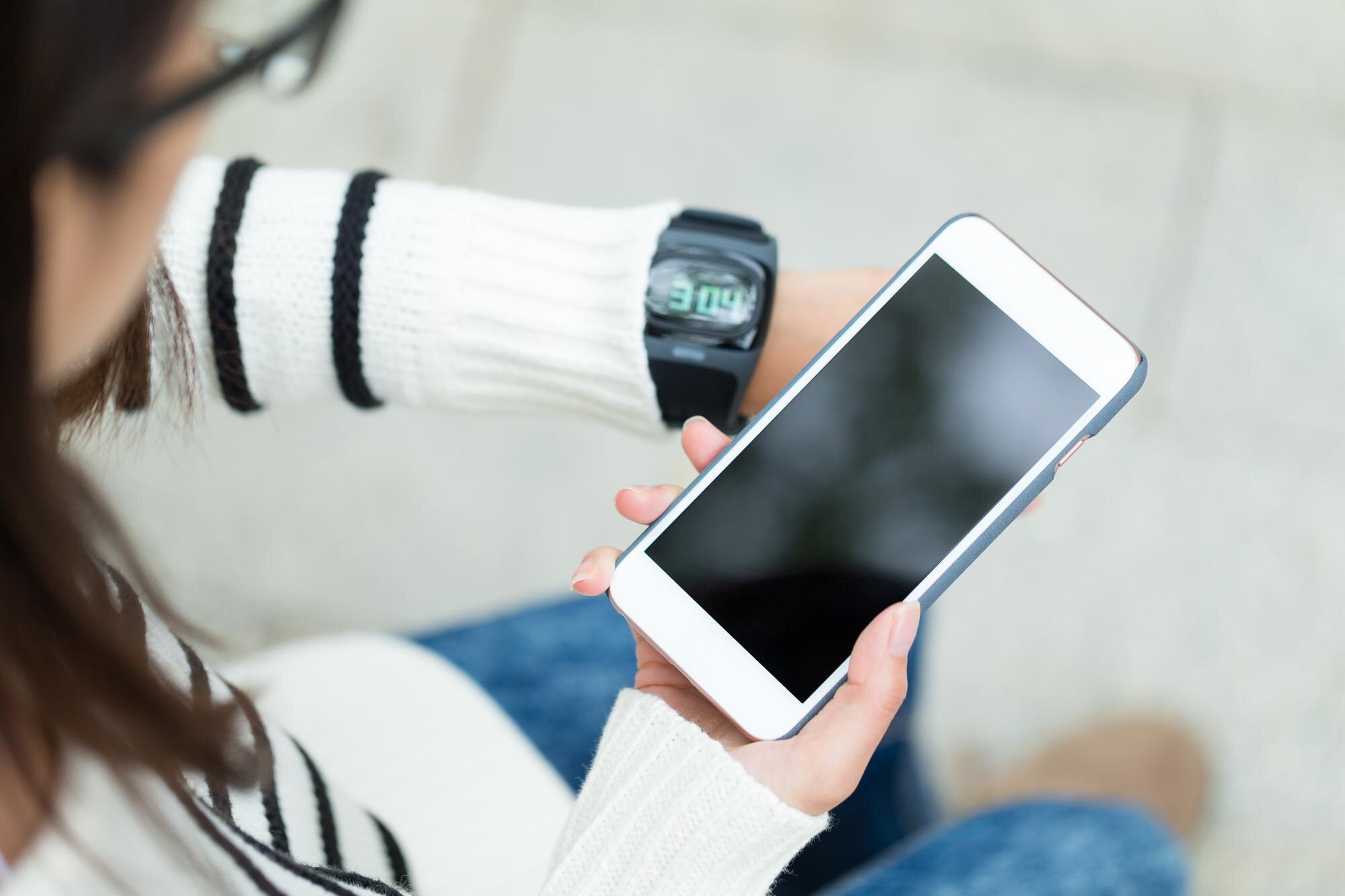 Kobieta łącząca telefon komórkowy i inteligentny zegarek