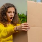 Szczęśliwa dziewczyna kupująca rozpakowuje pudełko kartonowe dostarcza paczkę zakupy online zakupy w domu