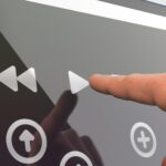 Users finger touching a play button on a digital devices screen
