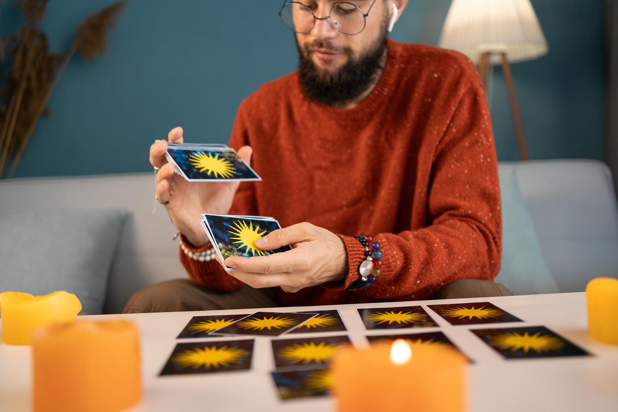 Young male fortuneteller with tarot cards recording video for blog at home