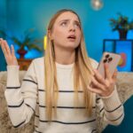 Caucasian woman looking shocked and disappointed after reading bad news or losing lottery on phone