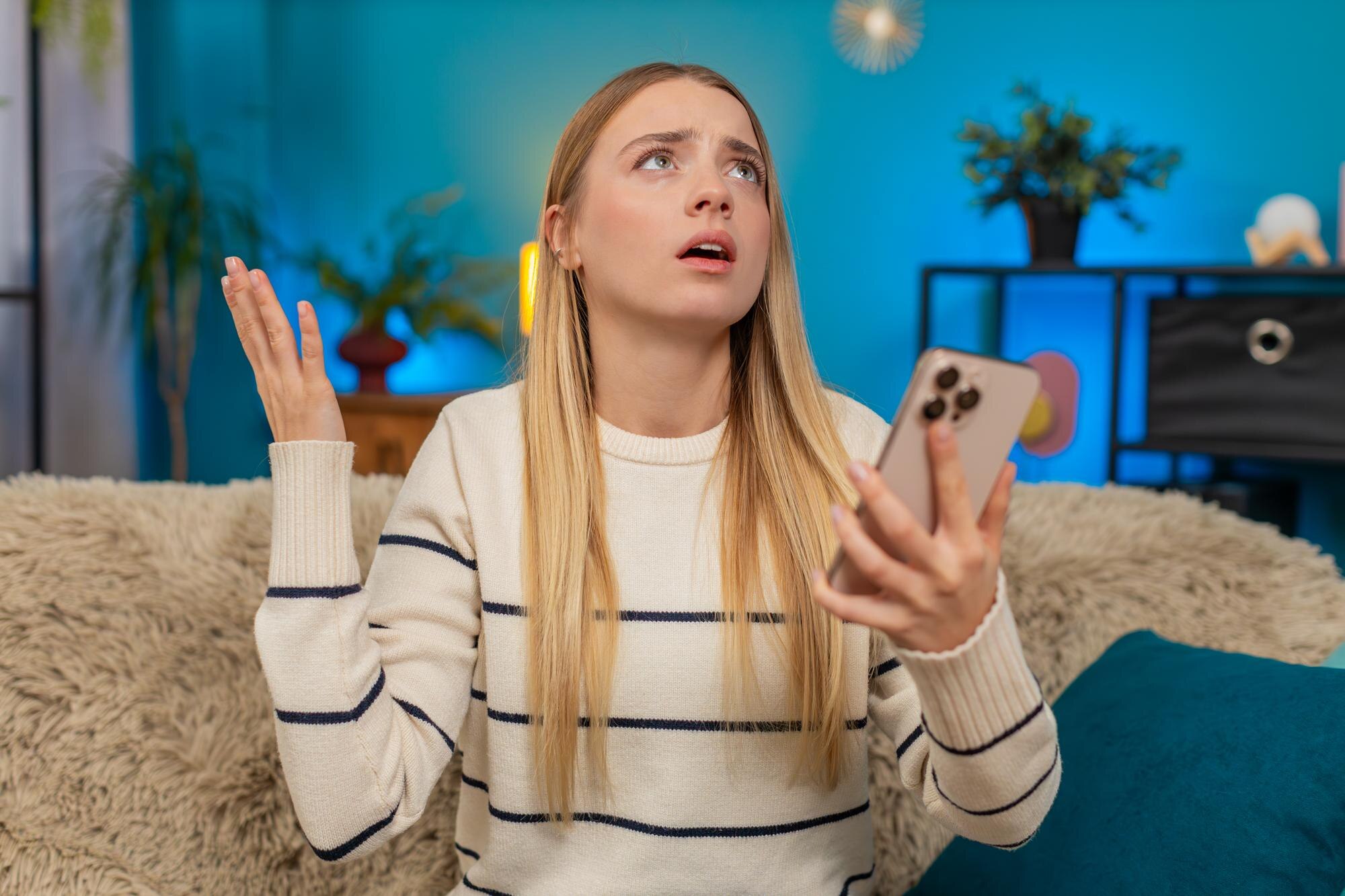 Caucasian woman looking shocked and disappointed after reading bad news or losing lottery on phone