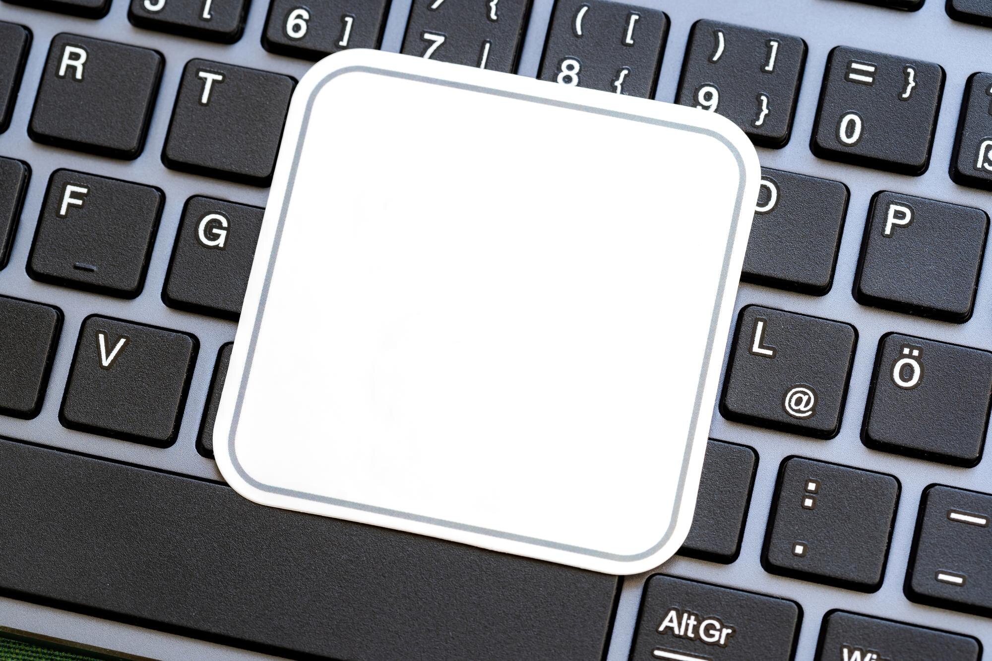 Full simple blank white square label on a laptop computer keyboard empty sticker template for logo design closeup detail modern business tech startup branding logo copy space concept nobody