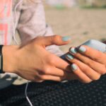 Dziewczyna na plaży w strojach sportowych słuchać muzyki ze słuchawkami na smartfonie