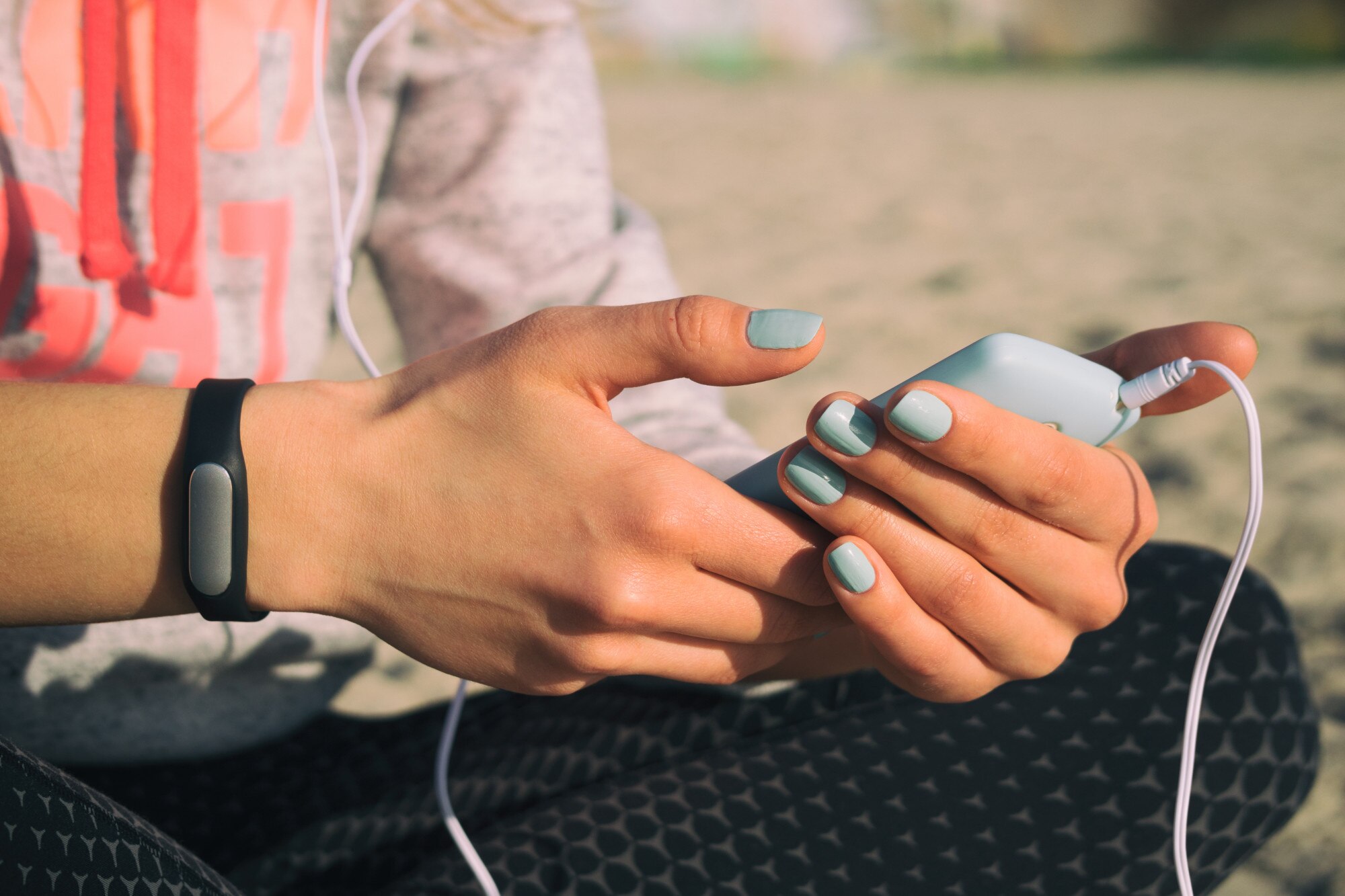 Dziewczyna na plaży w strojach sportowych słuchać muzyki ze słuchawkami na smartfonie