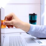 Mężczyzna wkłada notatkę do laptopa Outsourcing pracy w domu