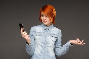 Rudzielec kobieta gapi się wprawiać w zakłopotanie na telefonie komórkowym