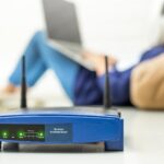 Zbliżenie routera przeciwko kobiecie używającej laptopa w domu