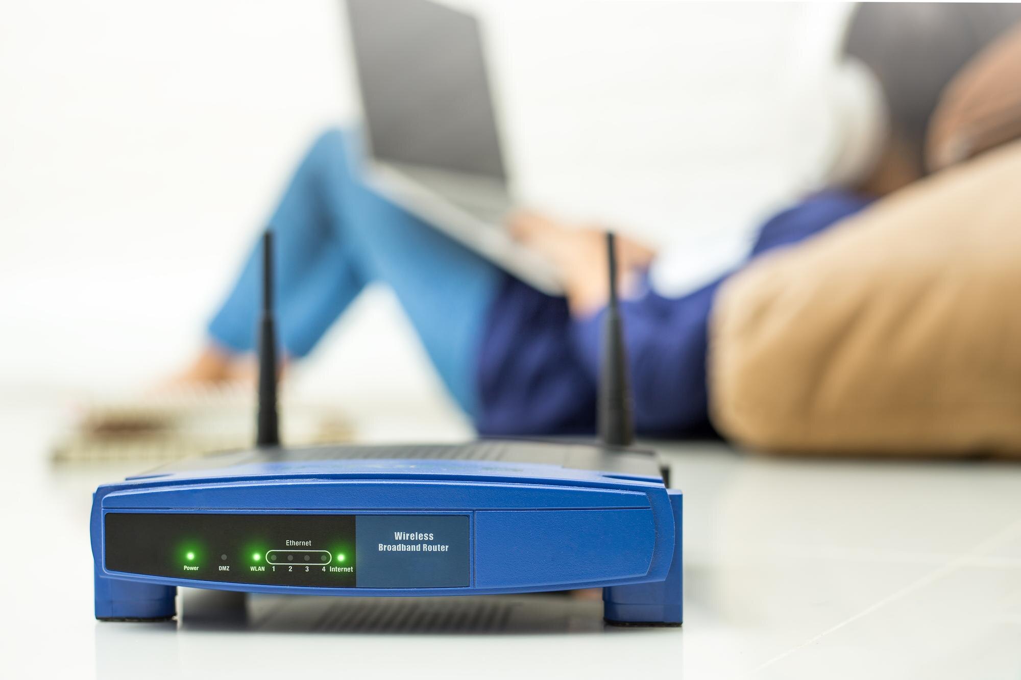 Zbliżenie routera przeciwko kobiecie używającej laptopa w domu
